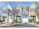 Charming colorful townhomes featuring attached garages and well-maintained landscaping at 103 Hundred Oaks Ln, Holly Springs, NC 27540