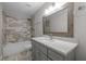 Bathroom featuring granite countertop, framed mirror, and tub with tiled shower and updated fixtures at 107 Bond St, Durham, NC 27707