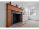 Close-up of a fireplace with a wooden mantel, decorative tiles, and bright window light at 2001 Rolesville Rd, Wake Forest, NC 27587