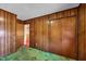 Bedroom featuring wood walls, carpet, closet, and a doorway leading to another room at 206 Eastway Ln, Graham, NC 27253