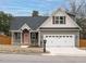 Charming home showcasing neutral siding, black roof, a two-car garage, and a welcoming peach-colored front door at 216 Cross St, Sanford, NC 27330