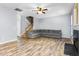 Open-concept living room with hardwood floors, gray sofa and a staircase leading to the upper level at 2506 Pepperstone Dr, Graham, NC 27253