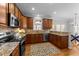 Well-lit kitchen with granite countertops, dark wood cabinets, stainless steel appliances, and a stylish patterned rug at 305 Covenant Rock Ln, Holly Springs, NC 27540