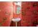 Unique powder room showcasing a pedestal sink and vibrant red wallpaper with a whimsical toile pattern at 3929 Browning Pl, Raleigh, NC 27609