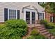 Close-up of the entryway with black double doors and sidelights, brick steps, and lush landscaping at 3929 Browning Pl, Raleigh, NC 27609
