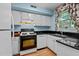 Functional kitchen with white cabinets, dark countertops, hardwood floors, and a window with patterned curtains at 3929 Browning Pl, Raleigh, NC 27609