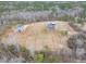 Scenic aerial view showcasing a charming home, detached garage, and potential garden area amidst a wooded landscape at 3958 Buckhorn Rd, Sanford, NC 27330