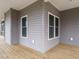 Corner view of a covered porch with wood floors, windows and gray siding at 3958 Buckhorn Rd, Sanford, NC 27330