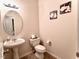 Cozy half bathroom featuring a pedestal sink, decorative mirror, and neutral tones at 5841 Wynmore Rd, Raleigh, NC 27610