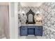 Charming bathroom features blue patterned wallpaper, and a blue vanity with a unique mirror and lighting at 612 W Chisholm St, Sanford, NC 27330