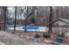 Community pool area with a fence, lifeguard chairs, and a playground surrounded by a forest at 6317 Lakeland Dr, Raleigh, NC 27612