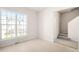 Sunlit room with large window, neutral walls and flooring, next to stairs to the second floor at 707 Sutter Gate Ln, Morrisville, NC 27560