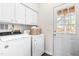 Efficient laundry room with a washer, dryer, storage cabinets, and a door leading to the outside at 707 Sutter Gate Ln, Morrisville, NC 27560
