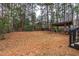 Wooded backyard featuring an outdoor grilling station with roof, fenced area and stairs to the deck at 7373 Newport Ave, Raleigh, NC 27613