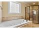 A tub with jets and a glass enclosed shower in the primary bath at 7373 Newport Ave, Raleigh, NC 27613