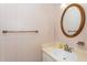 Cozy half bath featuring an oval mirror and neutral wallpaper at 751 Benchmark Dr, Raleigh, NC 27615