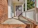 Charming front porch with a brick base, white railings, a decorative wreath, and a well-lit entryway, perfect for a warm welcome at 7634 Astoria Pl, Raleigh, NC 27612