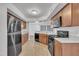 Well-lit kitchen with wood cabinets, granite counters, and stainless steel refrigerator at 7929 Falcon Rest Cir, Raleigh, NC 27615