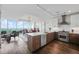 Open kitchen and dining area with stainless steel appliances and island, featuring city views from floor-to-ceiling windows at 110 N Corcoran St # 2304, Durham, NC 27701