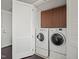 Efficient laundry area features stacked washer/dryer units and overhead storage cabinets at 110 N Corcoran St # 2304, Durham, NC 27701