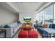 Comfortable living room with a grey sofa, blue armchairs, a coffee table, ottomans, and city views from the windows at 110 N Corcoran St # 2304, Durham, NC 27701