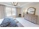 Bright bedroom with a large window, gray patterned curtains, and a wood dresser with decorative mirror at 1105 Freestone Rd, Durham, NC 27703