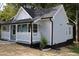 Charming home with a covered front porch, blue door and a white railing at 1210 Shaw St, Burlington, NC 27217