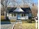 Charming home with a covered porch, blue front door, and landscaped front yard at 1210 Shaw St, Burlington, NC 27217