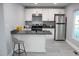 Well-lit kitchen with white cabinets, gray countertops, stainless steel refrigerator, and a breakfast bar at 1210 Shaw St, Burlington, NC 27217
