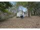 View of the home's backyard, with the home's exterior, trash cans, and overgrown trees at 1219 Carlton Ave, Raleigh, NC 27606