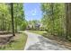 Long driveway leading to a large home nestled among mature trees, offering privacy and a peaceful setting at 209 Democracy Pl, Apex, NC 27523
