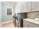 Well-lit laundry room with modern washer and dryer, complemented by ample white cabinetry and counter space at 209 Democracy Pl, Apex, NC 27523