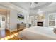 Comfortable main bedroom features hardwood floors, a fireplace, plantation shutters, and a TV at 209 Democracy Pl, Apex, NC 27523