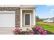 Close-up of townhome entry with stone accents, gray door, and landscaped flowers at 268 Moyer Dr, Graham, NC 27253