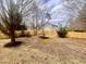 View of a partially-fenced backyard with mulch and young trees. A house is visible beyond the fence at 3 Azzi Ct, Durham, NC 27703