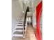 Bright foyer featuring wood floors, stairs with a black metal railing, and a red front door at 3 Azzi Ct, Durham, NC 27703