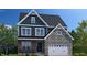 Two-story home with a combination of stone and blue siding, a two-car garage, and a charming front porch at 3190 Armeria Dr, Apex, NC 27502