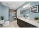 Bathroom with a dark vanity, granite countertop, framed mirror, glass shower, and soft blue walls at 400 W North St # 730, Raleigh, NC 27603