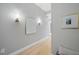 Hallway with hardwood floors, neutral-colored walls, and modern decorative wall sconces and framed art at 400 W North St # 730, Raleigh, NC 27603