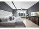 Bedroom with hardwood floors, gray accent wall, ceiling fan, TV and large windows with great city views at 400 W North St # 730, Raleigh, NC 27603