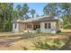 Scenic backyard view of a brick home with a covered patio and serene wooded surroundings at 5750 Nc Highway 49, Burlington, NC 27215