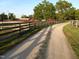 Scenic driveway leading to equestrian facilities, including fencing and red barn-style buildings in the background at 7027 Old 421 Rd, Liberty, NC 27298