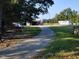 Gravel driveway leading to barn with trailer parked nearby under a mix of sun and shadows at 7027 Old 421 Rd, Liberty, NC 27298