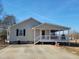 Home exterior featuring covered porch, concrete driveway, and professional landscaping at 7027 Old 421 Rd, Liberty, NC 27298