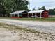 Exterior view of building featuring covered porch, red siding, and white trim at 7027 Old 421 Rd, Liberty, NC 27298