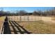 Large horse arena with metal gate and grass and dirt surface, providing an ideal space for training at 7027 Old 421 Rd, Liberty, NC 27298