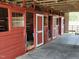Horse barn interior with individual stalls featuring red-painted wood and wire mesh at 7027 Old 421 Rd, Liberty, NC 27298
