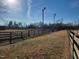 Horse facilities with an outdoor riding ring and surrounding grass pasture on a clear day at 7027 Old 421 Rd, Liberty, NC 27298