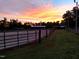 Horse facilities with outdoor riding ring surrounded by green pasture under a stunning sunset at 7027 Old 421 Rd, Liberty, NC 27298