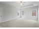 Main bedroom with tray ceiling, three large windows, carpet flooring, and neutral paint at 749 Aristocrat Ln, Knightdale, NC 27545